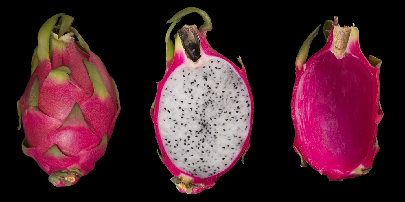 A whole dragon fruit, a halved fruit and an empty peel side by side