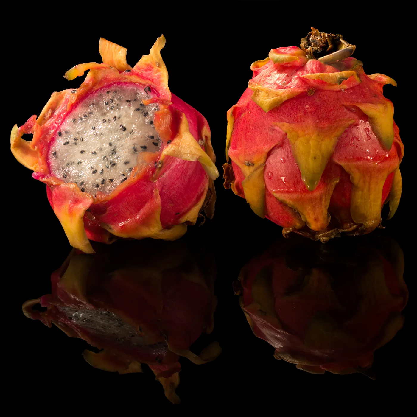 Whole and halved dragon fruit on a black background
