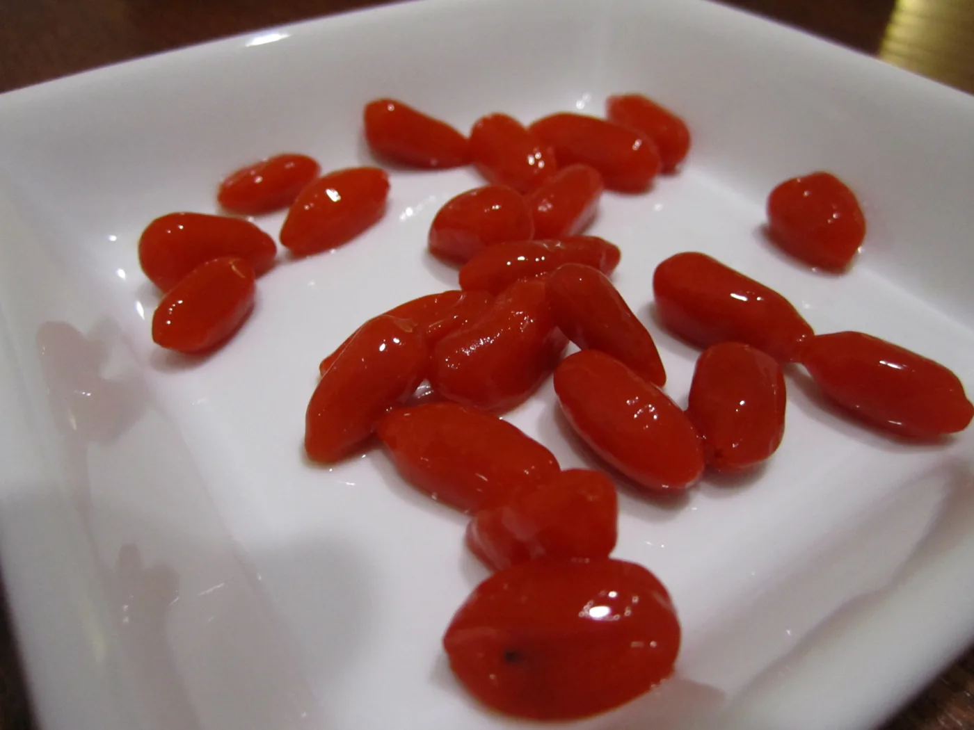 Shiny orange-red goji berries in a small white dish