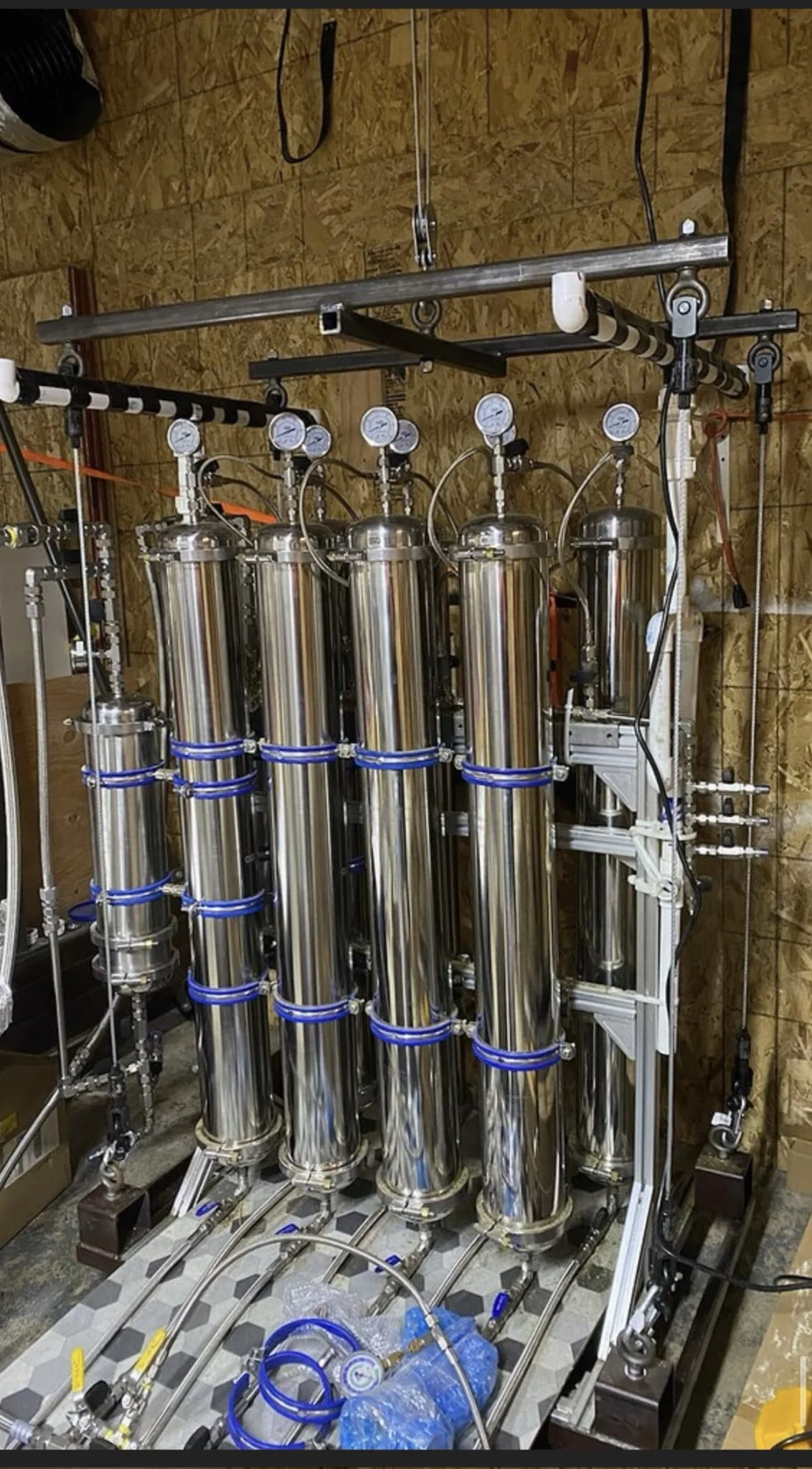 A tall rack of stainless steel extraction columns with blue fittings and tubing