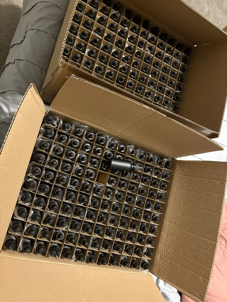 A cardboard box packed with rows of small dark glass tincture bottles